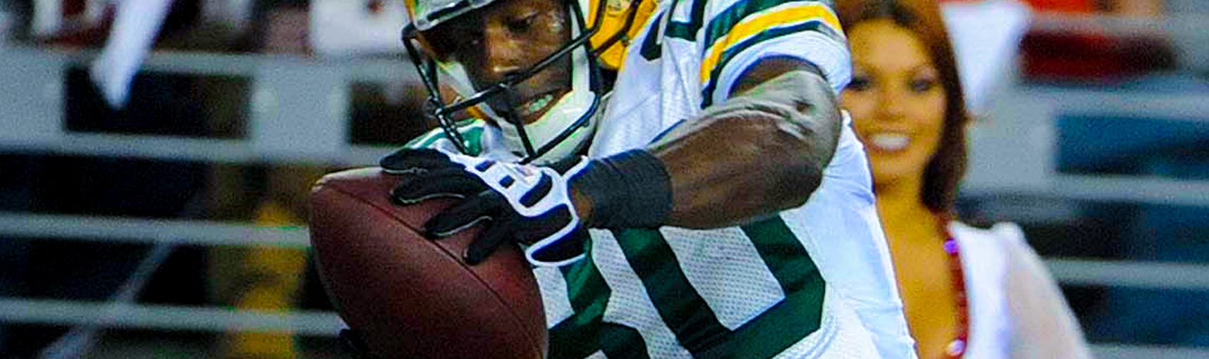 A man in a Green Bay Packers football uniform catches a football