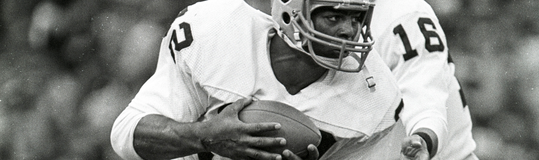 A man in a football uniform is holding a football