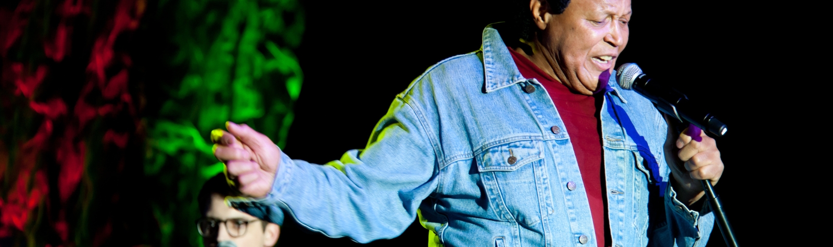 Singer Chubby Checker in a denim top and red turtleneck with a microphone in hand