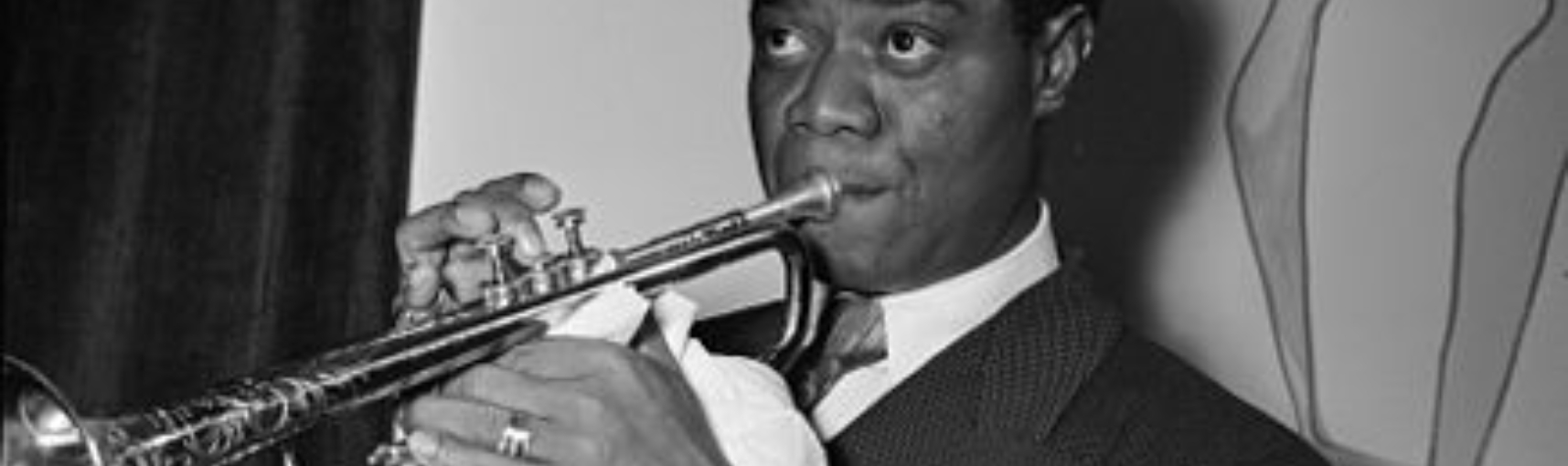Louis Armstrong with a saxaphone in his hands pressed against his lips